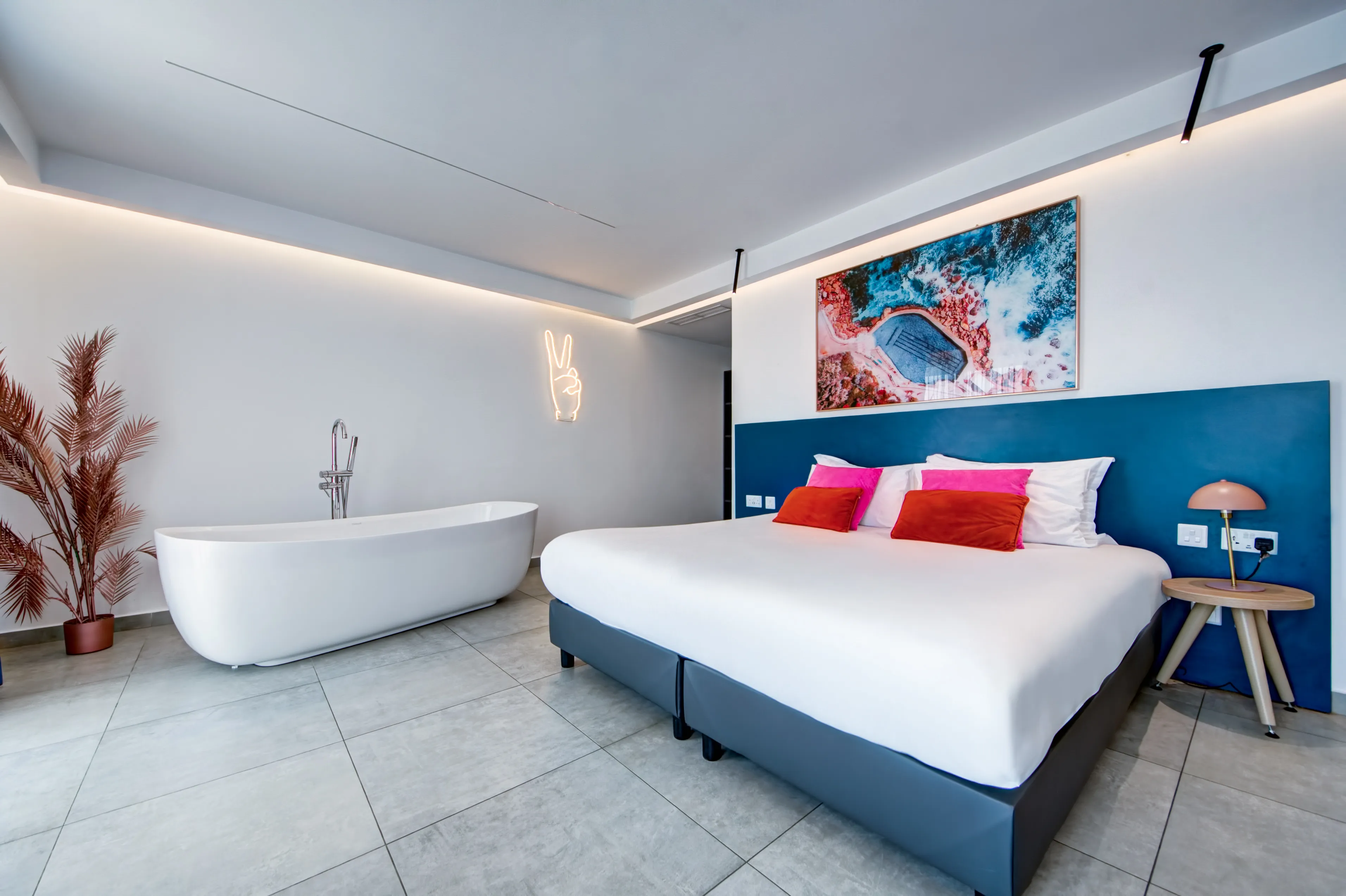 King Suite with freestanding bathtub, peace sign neon light and coastal art
